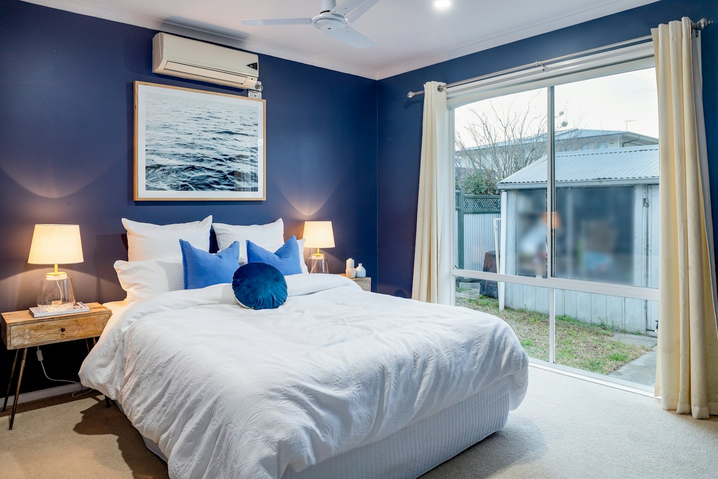 Bedroom with navy walls and illuminated lamps on bedside tables.