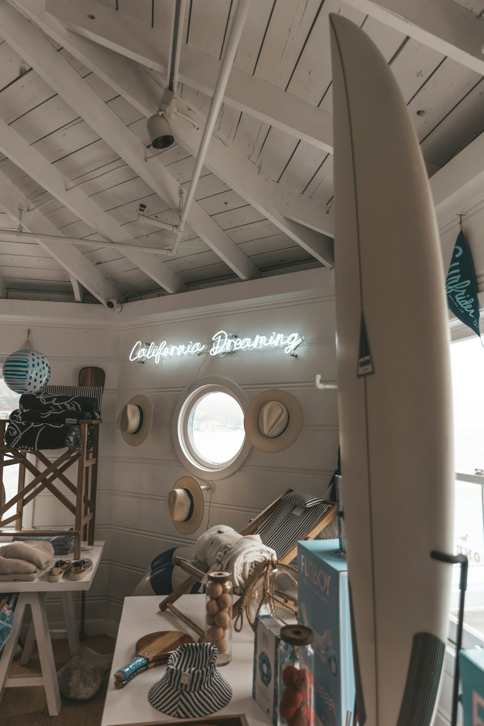 Coastal boutique with surfboard, hats, and neon sign.